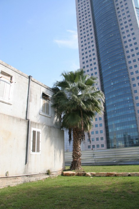 A modern skyscraper towers over a reconstructed building of the Sharona Templers colony