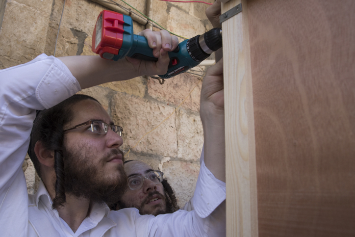Ultra orthodox Jewish men build a "Sukka" for the upcoming Jewish holiday of Sukkot, in the streets of the ultra orthodox neighborhood of Meah Shearim in Jerusalem. October 10, 2016. Sukkot commemorates the Israelites 40 years of wandering in the desert and a decorated hut or tabernacle (sukka) is erected outside religious households as a sign of temporary shelter. Photo by Nati Shohat/Flash90 *** Local Caption *** ???? ????? ????? ??????? ????? ???? ????? ????? ????? ??? ?????
