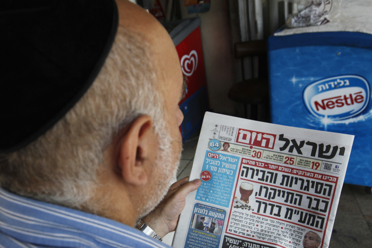 Israelis read in the daily newspaper about the raised taxes on cigarettes and beer, which went into effect as of last night. July 26, 2012. Photo by Miriam Alster/FLASH90  *** Local Caption *** ????? ???? ????? ?????