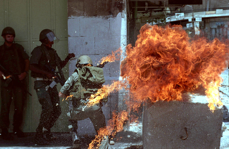 Israeli soldier runs off as a molotov cocktail explodes beside him during clashes with Palestinians