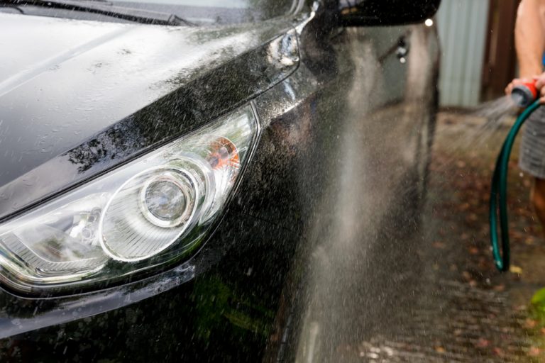 A,Man,Is,Washing,Black,Car,In,Open,Air