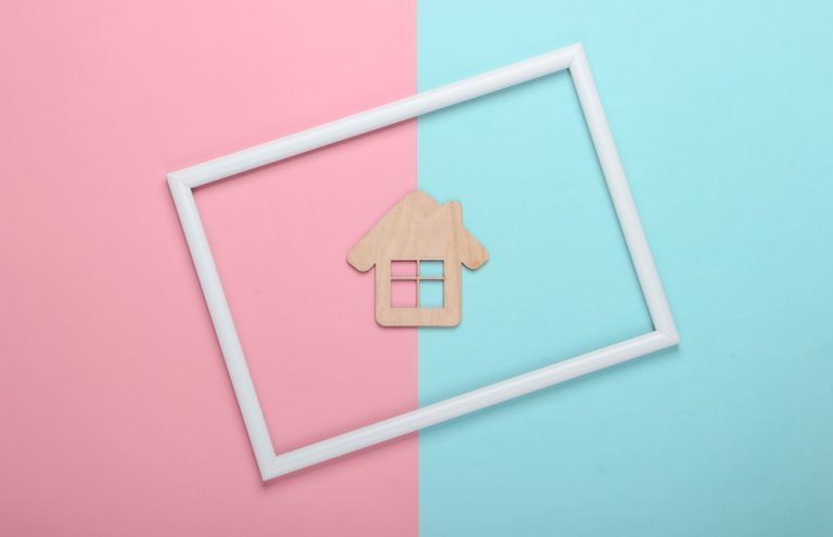 mini-wooden-house-pink-blue-pastel-surface-with-white-frame
