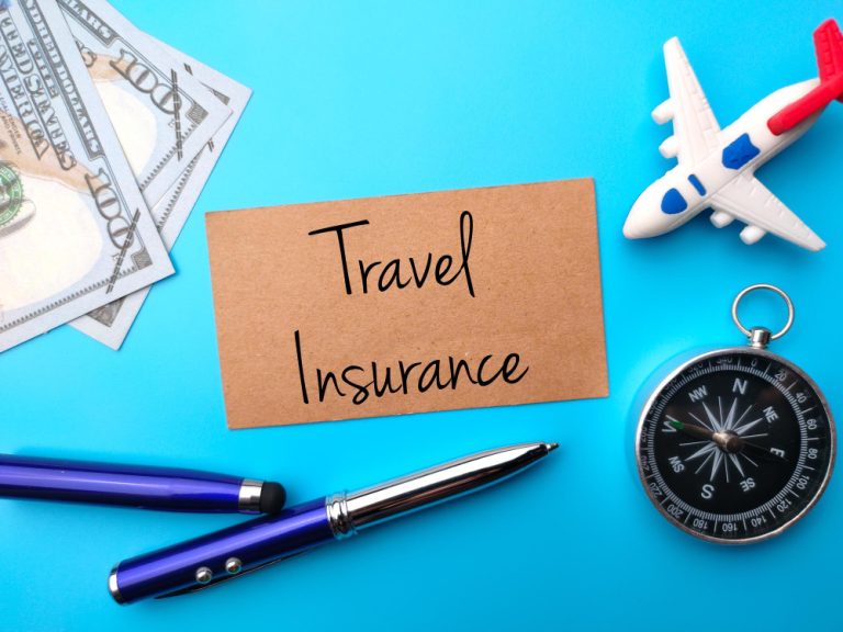 banknotespencompass-toy-airplane-with-text-travel-insurance-blue-background