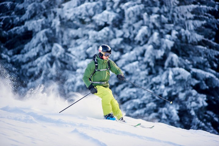 skier-backpacker-skiing-down-slope-raising-blizzard-snow-powder-picturesque-forest-scenery-blurred-background
