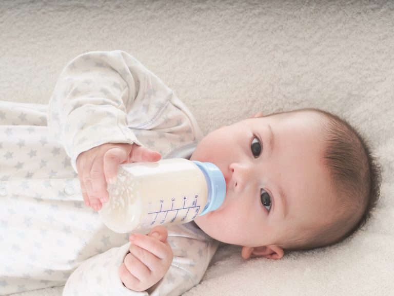 Baby boy  drinking milk from the bottle at home