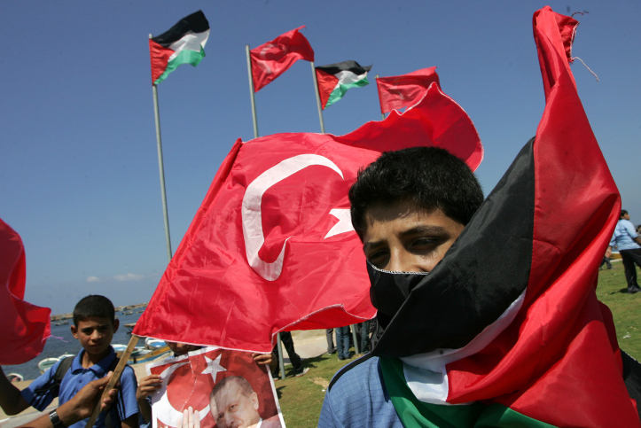 Palestinian students hold up pictures of Turkish Prime Minister Recep Tayyip Erdogan and the Turkish and Palestinian flags during rally beckoning him to visit the Gaza Strip at the port in Gaza City