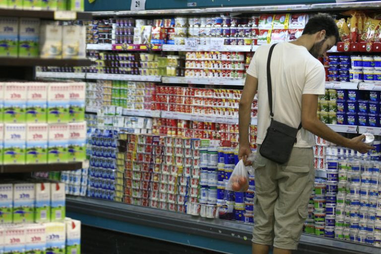 Shopper looks to purchase cheese in the diary aisle in supermarket