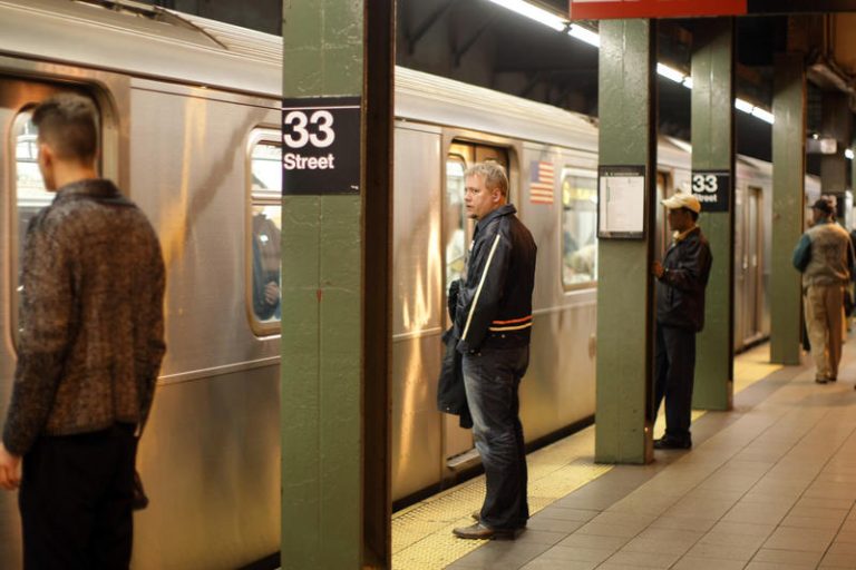 People stand on a platform waiting to get on the subway