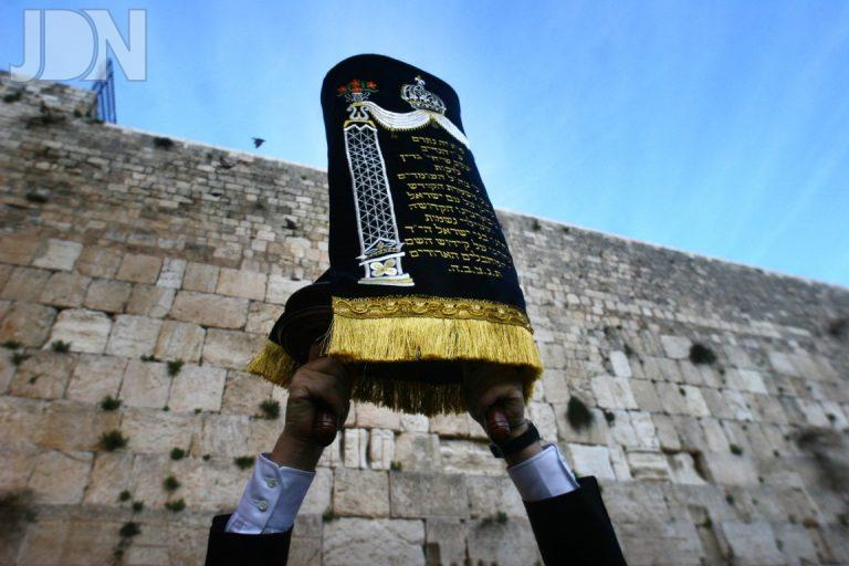 Ultra orthodox Jewish man holds up a Torah Scroll at the Western Wall in Jerusalem