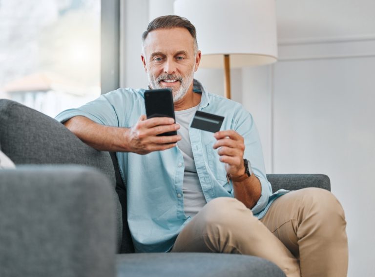 Credit,Card,,Mobile,Phone,And,Mature,Man,On,Sofa,For
