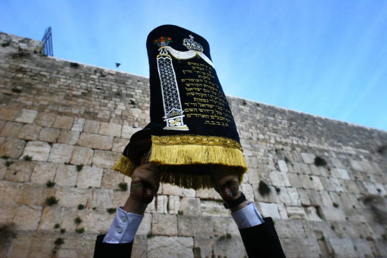 Ultra orthodox Jewish man holds up a Torah Scroll at the Western Wall in Jerusalem