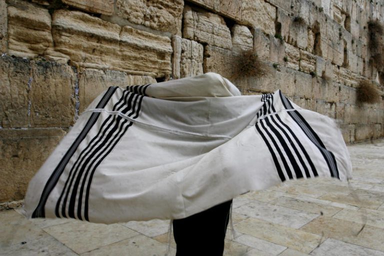 Man putting on his prayer shawl by the Western Wall in Old City, Jerusalem